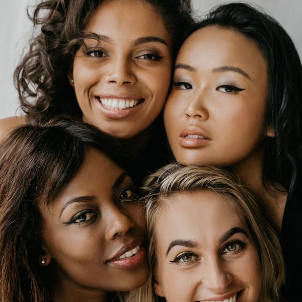 Group of diverse women smiling and supporting each other.